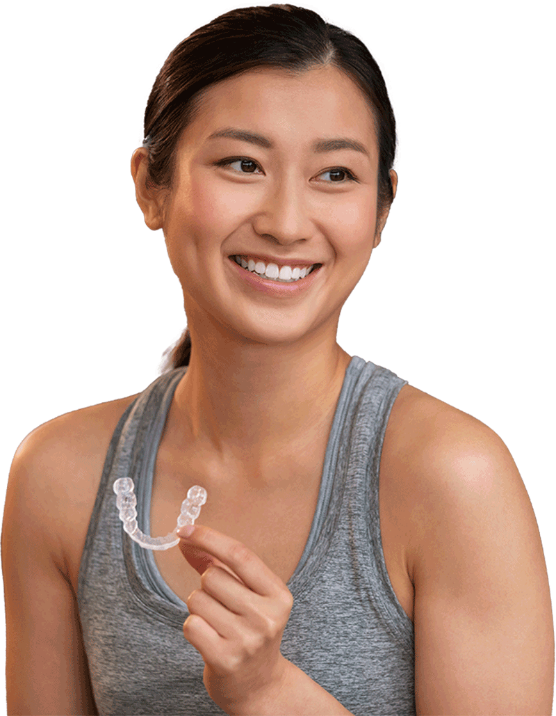 Smiling woman holding an Invisalign clear aligner