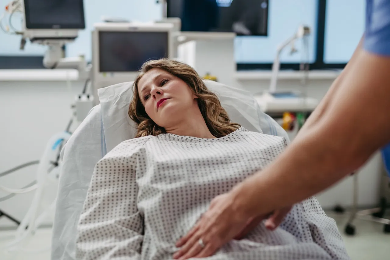 A woman lies on a hospital bed and is consulted by a doctor