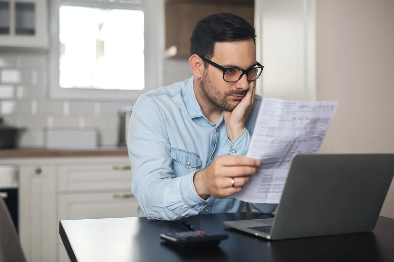 A man working on a computer looks at a document