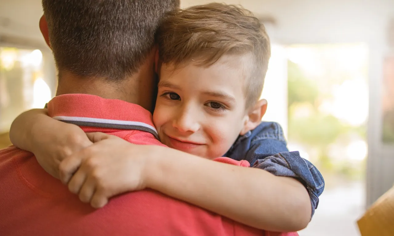 A little boy in arms hugging his father