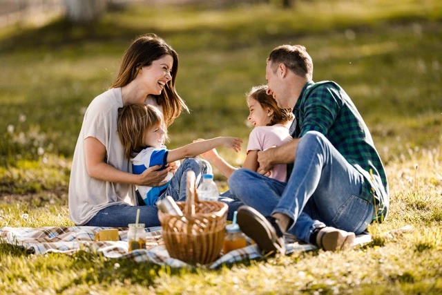 Photo of a family sitting on the grass and having a picnic